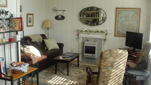 A living room with a fireplace, a sofa, a coffee table, and a television. - Stone Meadow Resort (Eureka Springs)