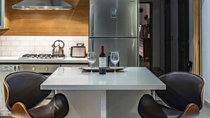 A modern kitchen with a stainless steel refrigerator, a gas stove, and two black chairs. - Casa Iguana at Carranza (Puerto Vallarta)