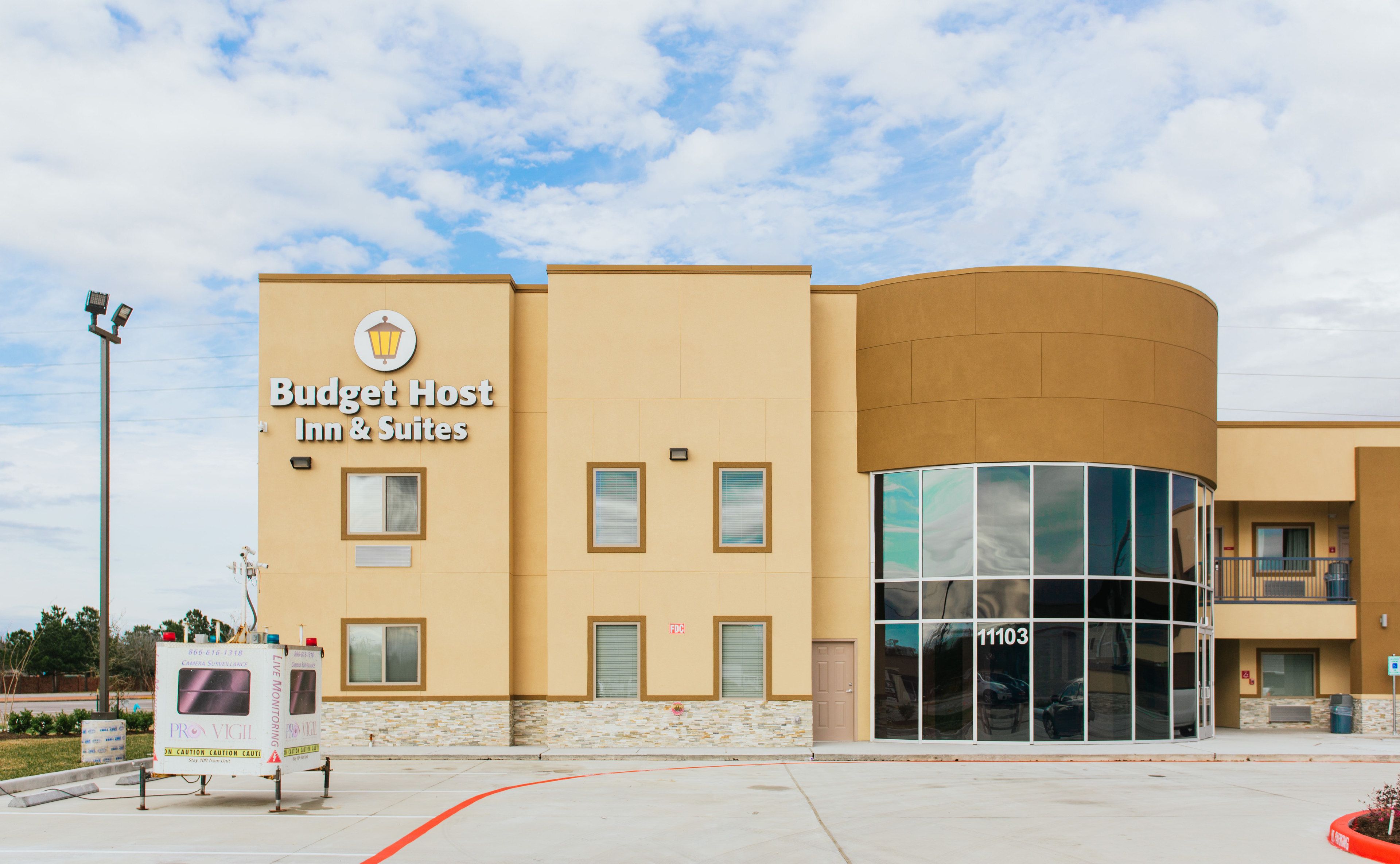 Um Budget Host Inn & Suites com design moderno, apresentando uma fachada curva e janelas amplas.