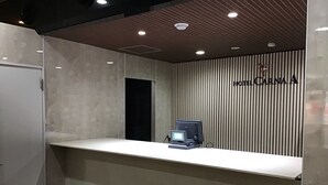 A reception desk with a computer, a wooden slatted wall, and a sign that reads "HOTEL CARNA A". - Hotel Carna A (Kumamoto)
