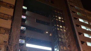 A multi-story building with a modern design, featuring a prominent entrance with a sign. - Hotel Carna A (Kumamoto)