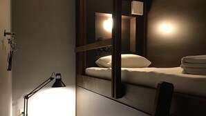 A modern hotel room with a single bed, a bedside lamp, and a mirror reflecting the room's interior. - Hotel Carna A (Kumamoto)