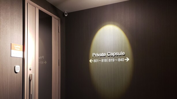 A private capsule room with a door marked 'Ladies Floor' and a wall-mounted sign indicating 'Private Capsule' with contact numbers. - Hotel Carna A (Kumamoto)