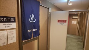 A men's bathroom with a blue towel hanging on the wall, a sign indicating it's for men, and a separate sign for ladies only. - Hotel Carna A (Kumamoto)