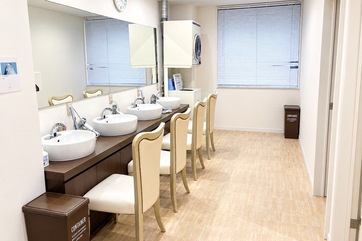 A hotel bathroom with multiple sinks, a large mirror, and a trash bin.