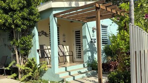 A two-story house with a covered porch, a small garden, and a white picket fence. - Coralina- Beautiful Cottage for Two...a Great Value (Vieques)