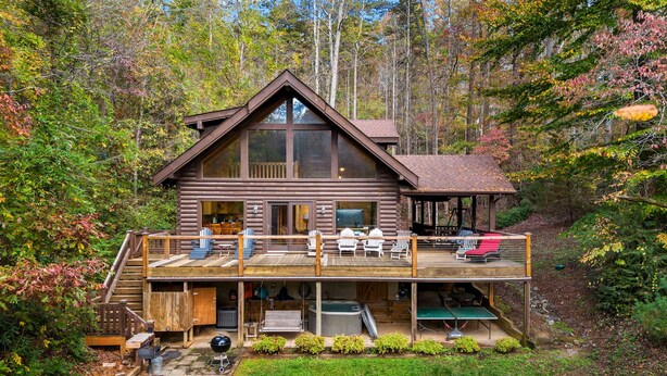 Une cabane en rondins dotée d’une terrasse, d’un espace salon extérieur et d’un jacuzzi.