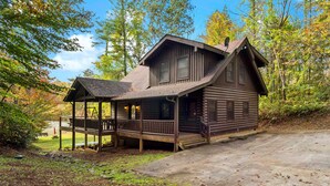 Une cabane rustique en rondins de bois, dotée d’un porche, d’une cheminée et d’une antenne parabolique.