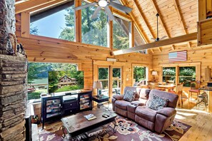 Une cabine spacieuse dotée d’un grand téléviseur, de sièges confortables et offrant une vue sur un lac.