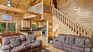 L’intérieur d’une cabane en bois comprend un coin repas, une cuisine et un escalier menant à une mezzanine.