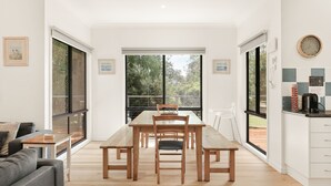 Una cucina moderna con zona pranzo, ampie finestre e vista sul verde.