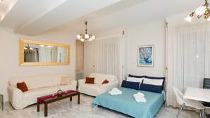 Ein modernes Hotelzimmer mit einem großen Bett, zwei Sofas, einem Esstisch und einem großen Spiegel.
