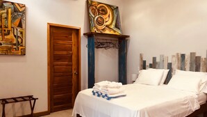 A bedroom with a bed, a wooden door, and two abstract paintings on the walls.