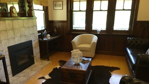 A living room with a fireplace, a leather sofa, a patterned rug, and a cowhide rug. - Ada Cottage - Warburton, Yarra Valley (Warburton)