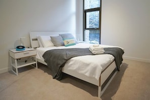 Relax in a serene bedroom with a single bed, white headboard, and a cozy throw blanket.