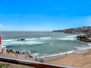 A coastal view with a beach, waves, and a town in the background.