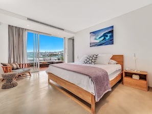 A modern bedroom with a large bed, a view of the city, and a balcony.
