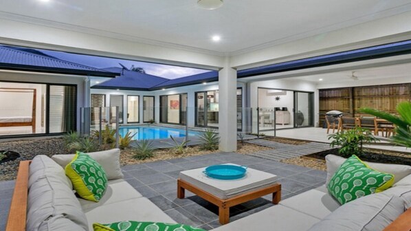 Relax by the pool in this inviting outdoor space, featuring a comfortable seating area and a patio with a deck.