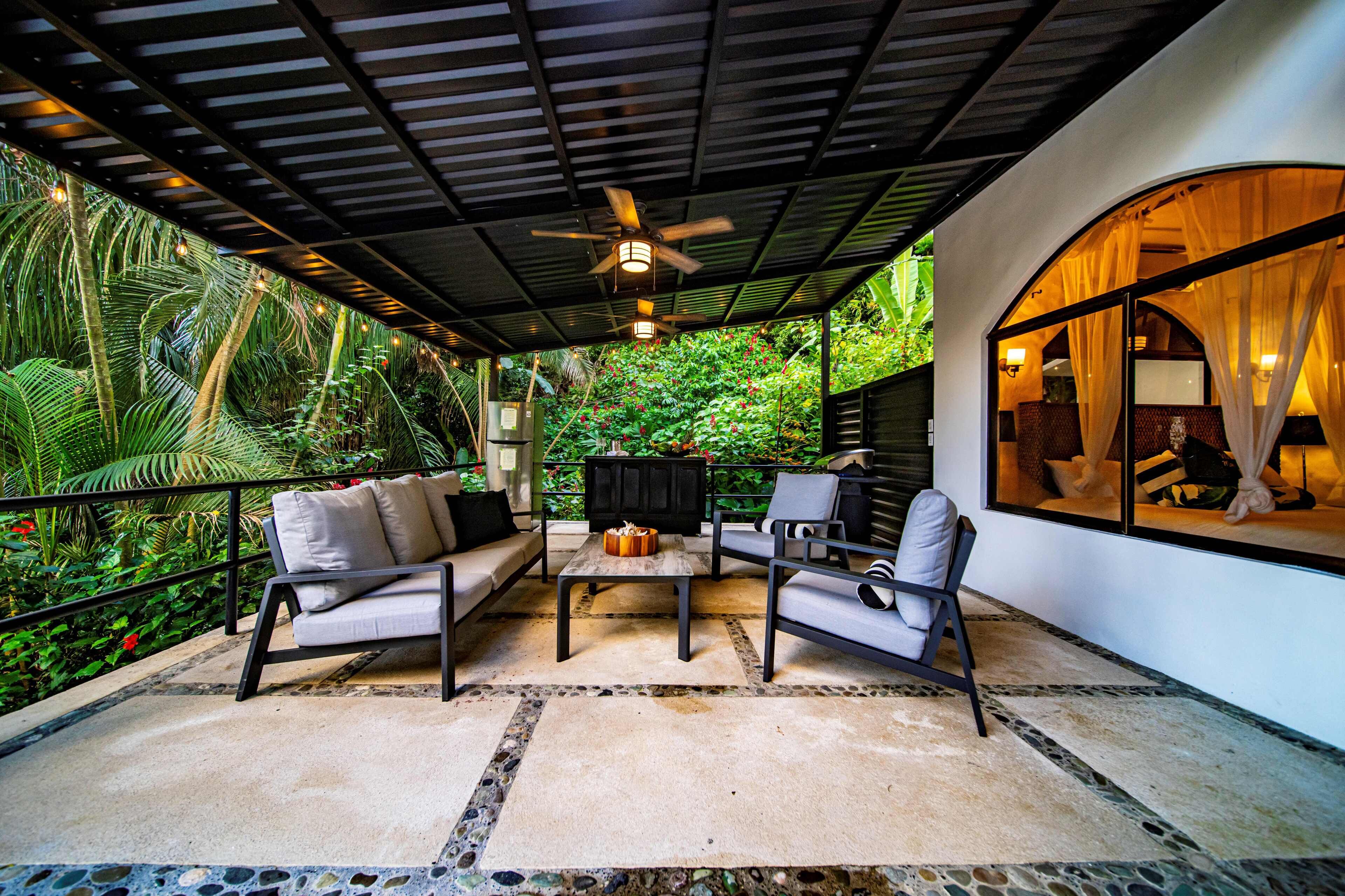 An outdoor seating area with a ceiling fan, a sofa, a chair, and a table.