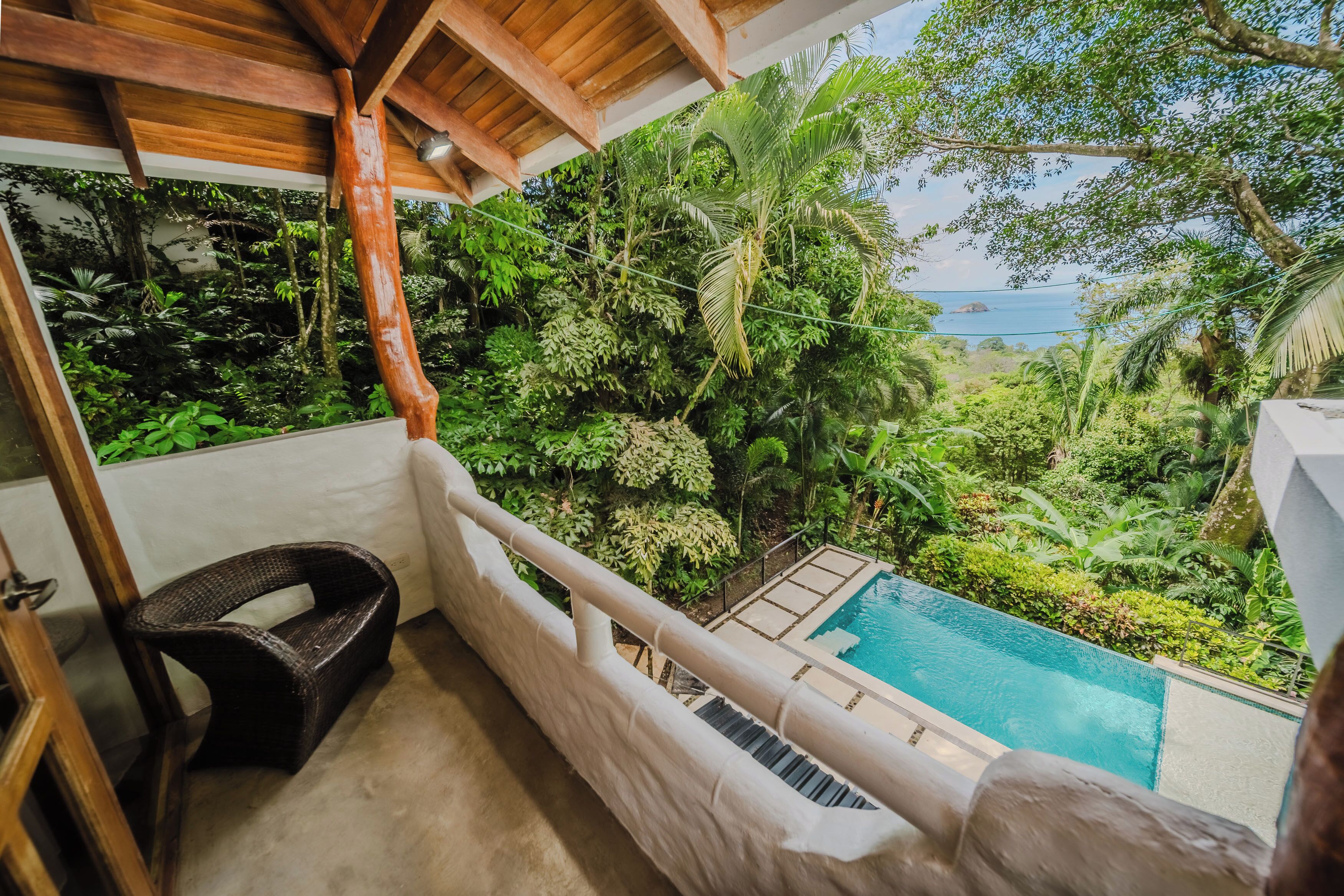 A balcony with a view of a pool and lush greenery.