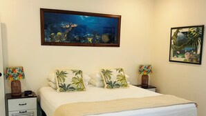 Un dormitorio con una cama, dos mesitas de noche, un cuadro colgado en la pared y una lámpara de pie.