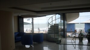 Un interno moderno con parete in vetro che offre vista sulla spiaggia e una scala a chiocciola.