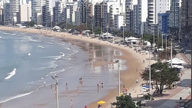 Una spiaggia con un litorale sabbioso, alcuni ombrelloni e una barca gialla.
