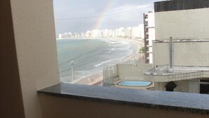 Vista di una spiaggia con un arcobaleno, una piscina e un edificio con balconi.