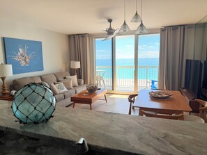 A room with a sofa, a dining table, a TV, and a view of the ocean. - BEACHFRONT condo.Stunning Gulf views at Destin's #1 resort Luxe Cozy 5-star stay (Destin)