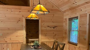 A wooden interior with a dining table, chairs, and hanging lamps. - Paradox Lake - The Carriage House   (Severance)