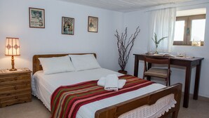 Un dormitorio ordenado con cama, mesita de noche, lámpara y escritorio con silla.