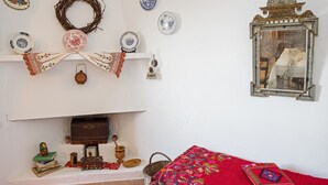 Una habitación con chimenea, un espejo y varios objetos decorativos, incluyendo platos y un tapete.