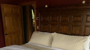 Una cama de madera con ropa blanca en una habitación con paneles de madera y una puerta.