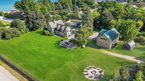 An aerial view of a residential property with a large lawn, a swimming pool, and a house with a green roof.