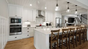 A modern kitchen with white cabinetry, stainless steel appliances, and a central island with bar stools.