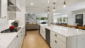 A modern kitchen with white cabinetry, a large island, and pendant lighting.