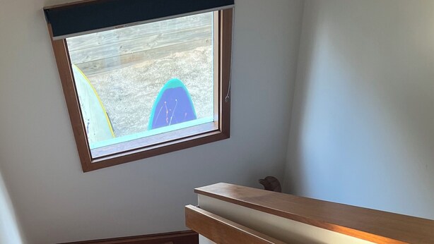 Eine Holztreppe mit Handlauf und einem Fenster darüber.