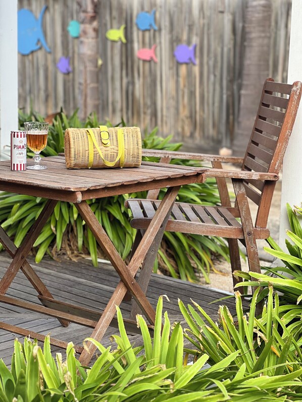 Juego de mesa y silla de madera al aire libre, con una cesta de mimbre y una jarra de cerveza.