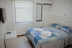A bedroom with a bed, a TV, a window with blinds, and an air conditioning unit. - BEST OF GUARAJUBA, GENIPABU SUMMER HOUSE, BEACHFRONT (Camaçari)