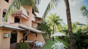 Un edificio con patio, mobiliario exterior y palmeras.