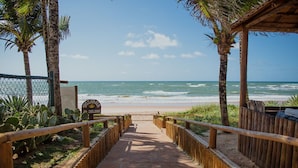 Un sendero que lleva a una playa con palmeras y una valla de madera.