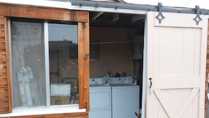 Een kleine wasruimte met een houten gevel, een groot raam en een witte deur.