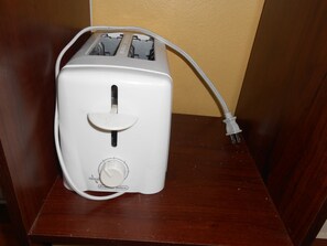 Un torrador blanc amb un cable d'alimentació sobre una superfície de fusta.