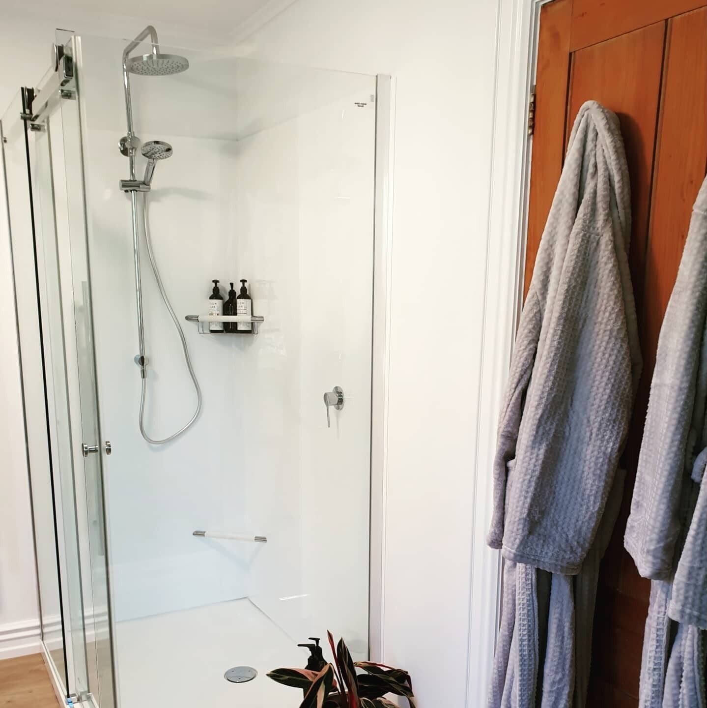 Une salle de bain moderne avec une douche à parois de verre, un porte-serviettes avec deux serviettes et une petite étagère contenant des articles de toilette.