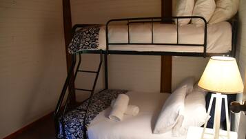 Een slaapkamer met een stapelbed, een bedlampje en beddengoed met een patroon.