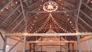 An interior with a high ceiling, wooden beams, and string lights. - The Mill House, year around Country Home & Historic Grist mill w/ 2 Kayaks (Posen)