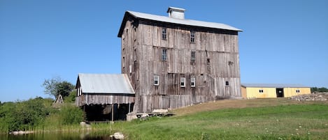 A large, rustic wooden building with multiple windows and a small attached structure.