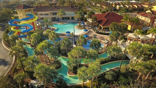 Un complexe hôtelier doté d’une grande piscine, de toboggans aquatiques et de palmiers.