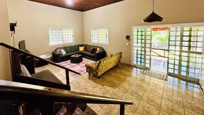 A spacious living area with a wooden ceiling, a sectional sofa, a patterned armchair, and a staircase. - Property in Torrinha - near Brotas (Torrinha)