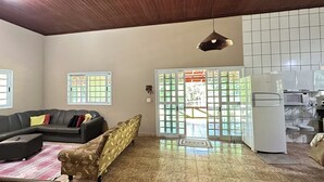 A spacious living area with a wooden ceiling, a sofa, a patterned armchair, a refrigerator, and a tiled floor. - Property in Torrinha - near Brotas (Torrinha)